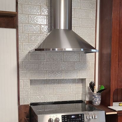 A kitchen with a stove and a hood on the wall.