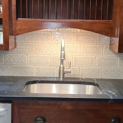 A kitchen sink with a stainless steel faucet and a wooden cabinet above it.