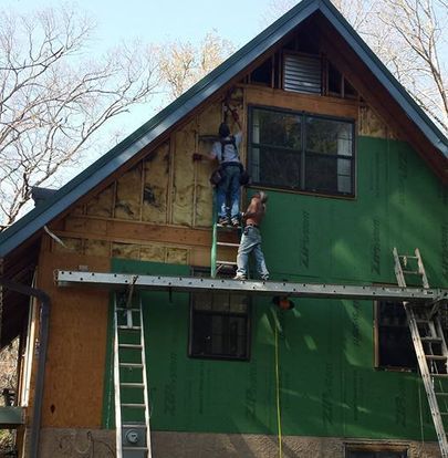 A man is standing on a ladder on the side of a house