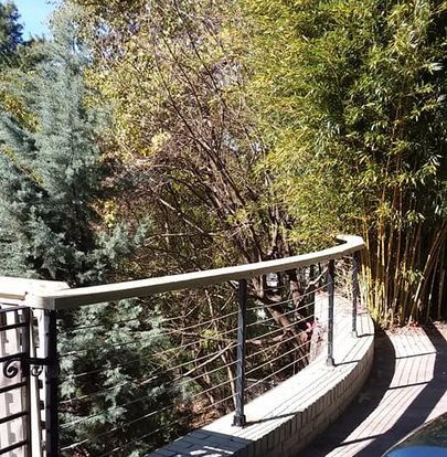 A wooden deck with a metal railing surrounded by trees