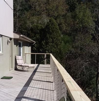 A deck with a chair on it and trees in the background