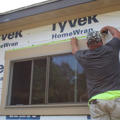 A man is measuring a window with a tape measure