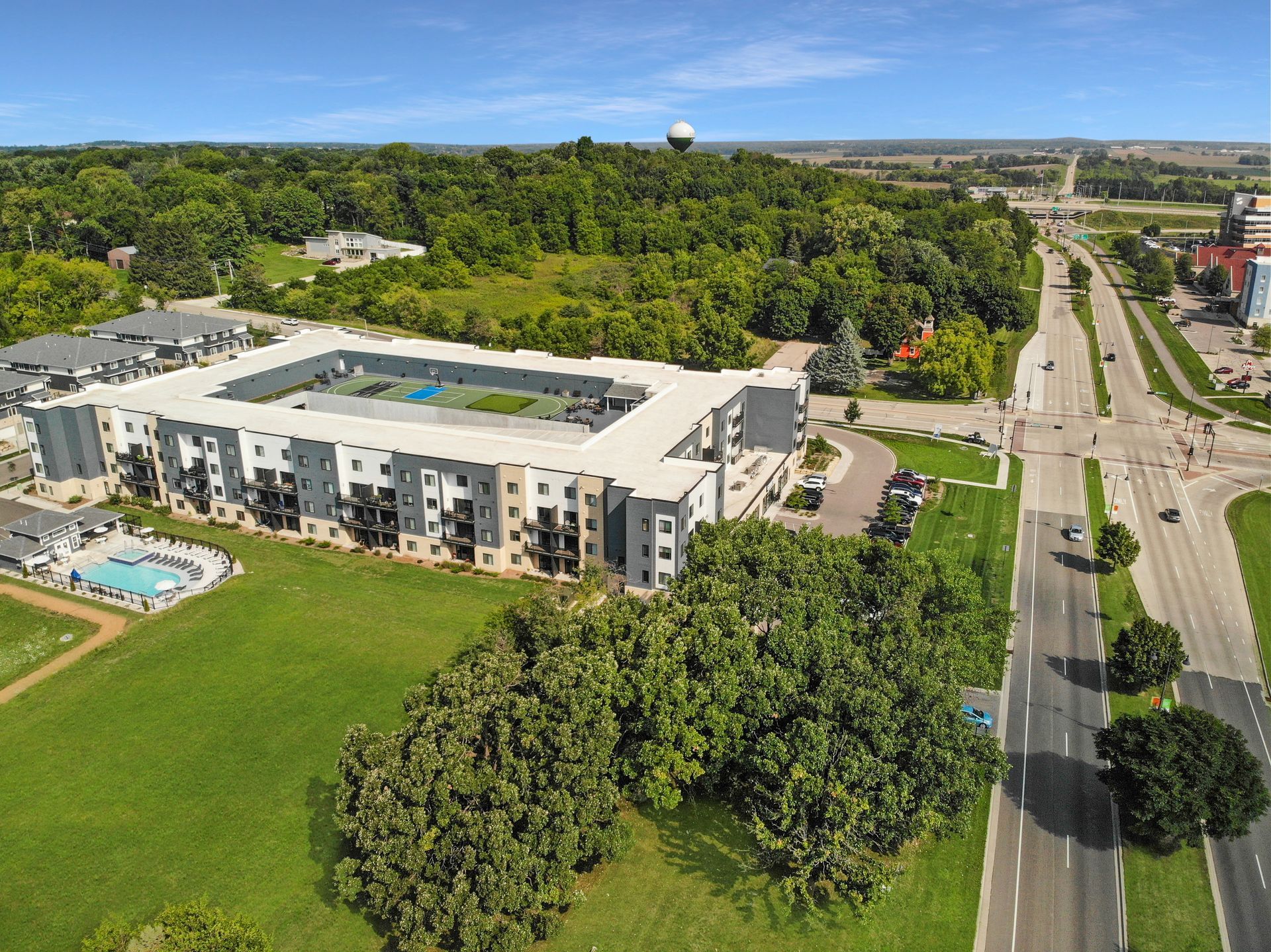 An aerial view of a large building surrounded by trees and a road.