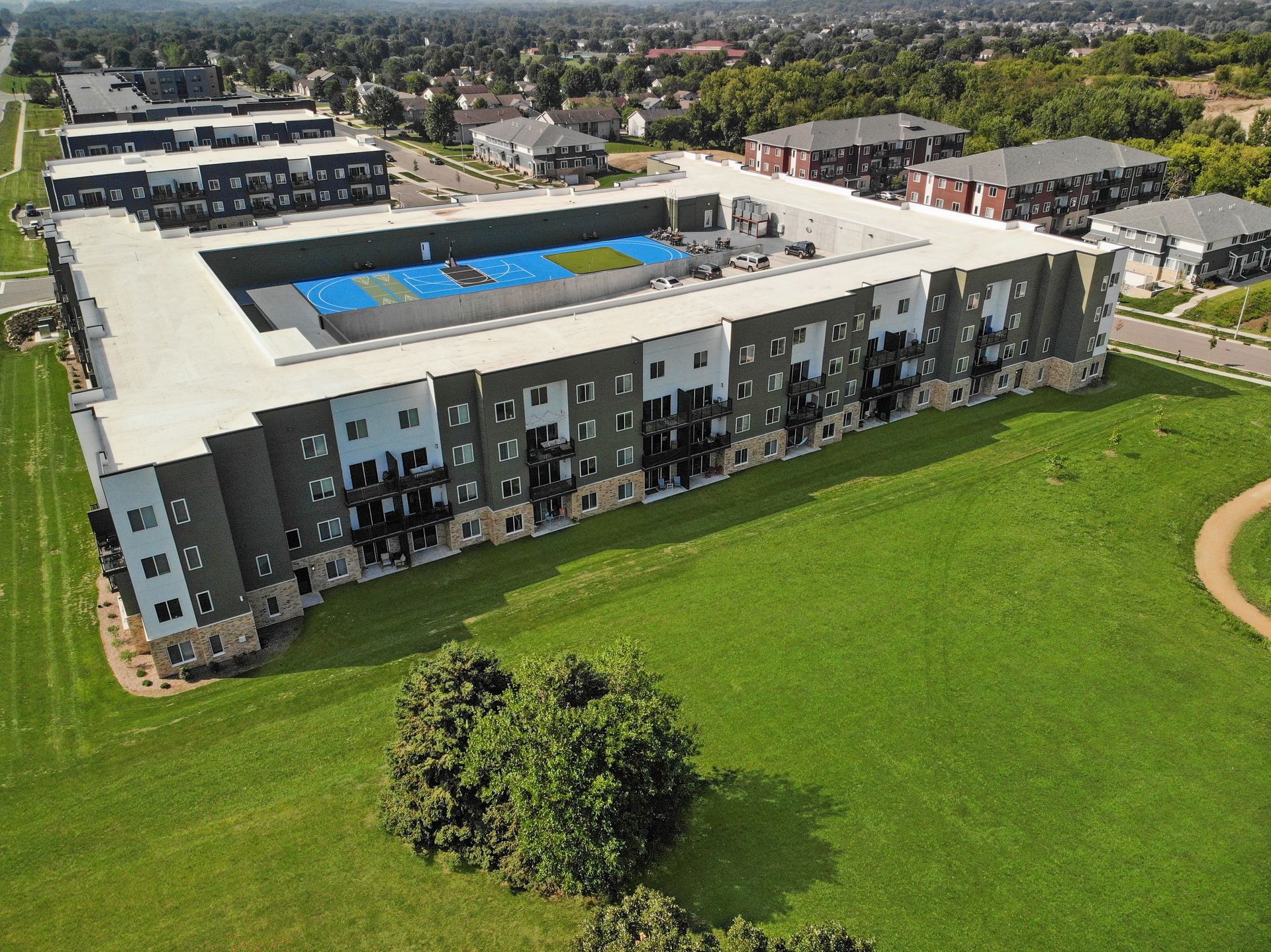 An aerial view of a large apartment building with a baseball field in front of it.