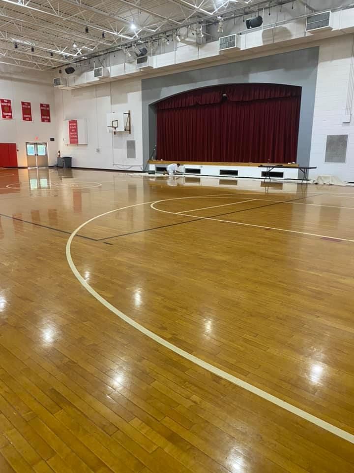 An empty gym with a wooden floor and a stage.