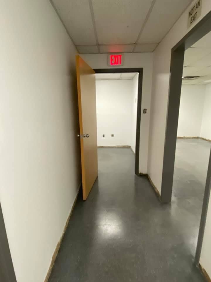 A hallway with a red exit sign on the wall
