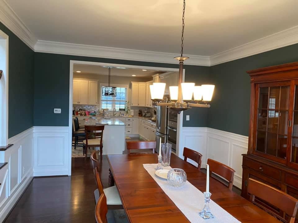 A dining room with a long table and chairs and a chandelier hanging from the ceiling.