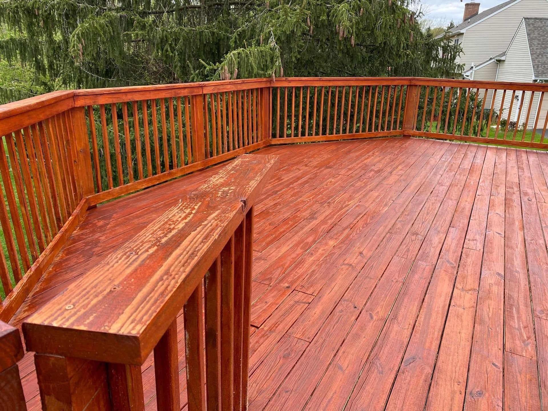 A large wooden deck with a bench and railing.