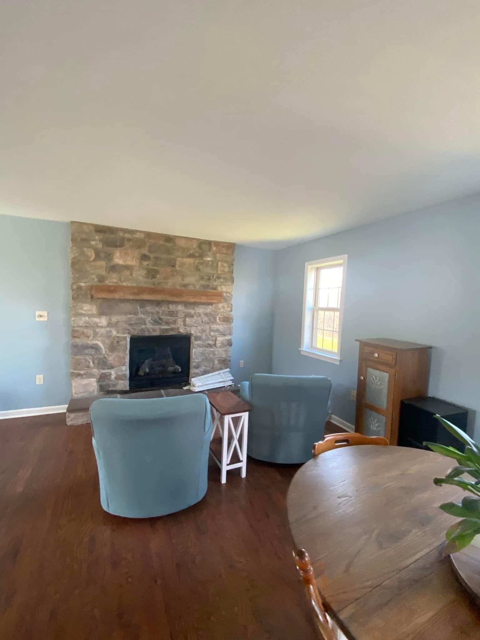 A living room with a fireplace , chairs and a table.