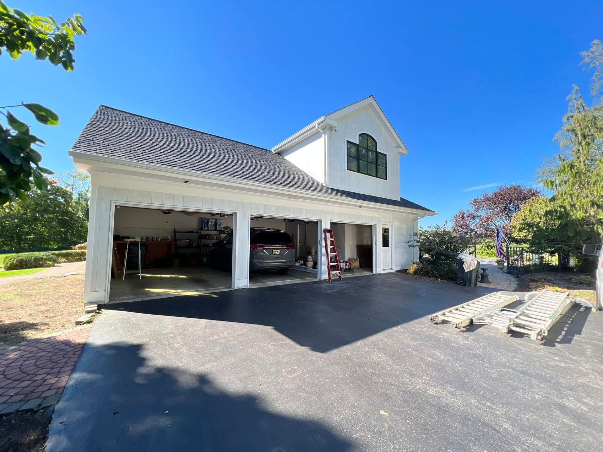A white house with a car parked in the garage.