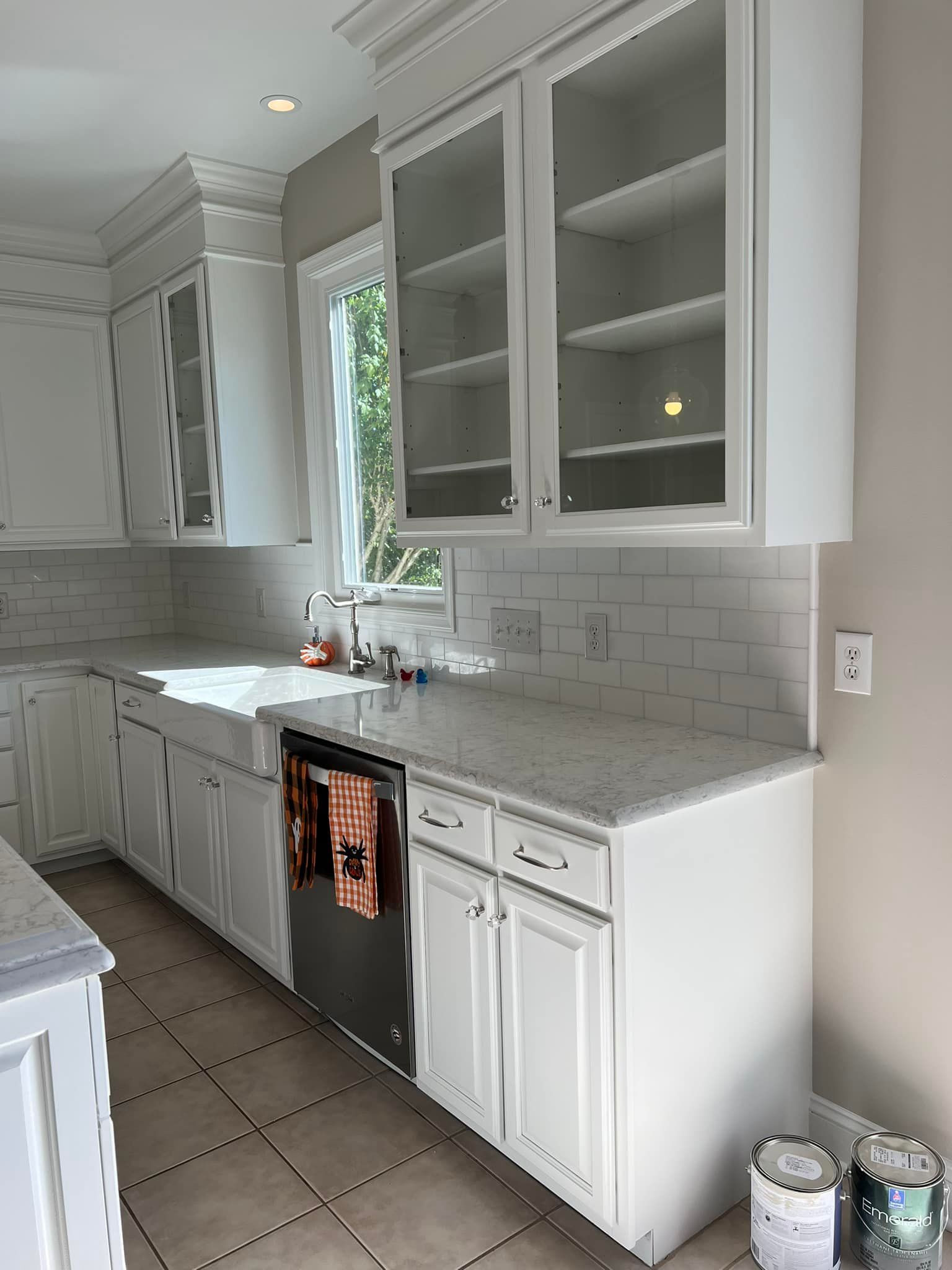 A kitchen with white cabinets , a sink , and a dishwasher.