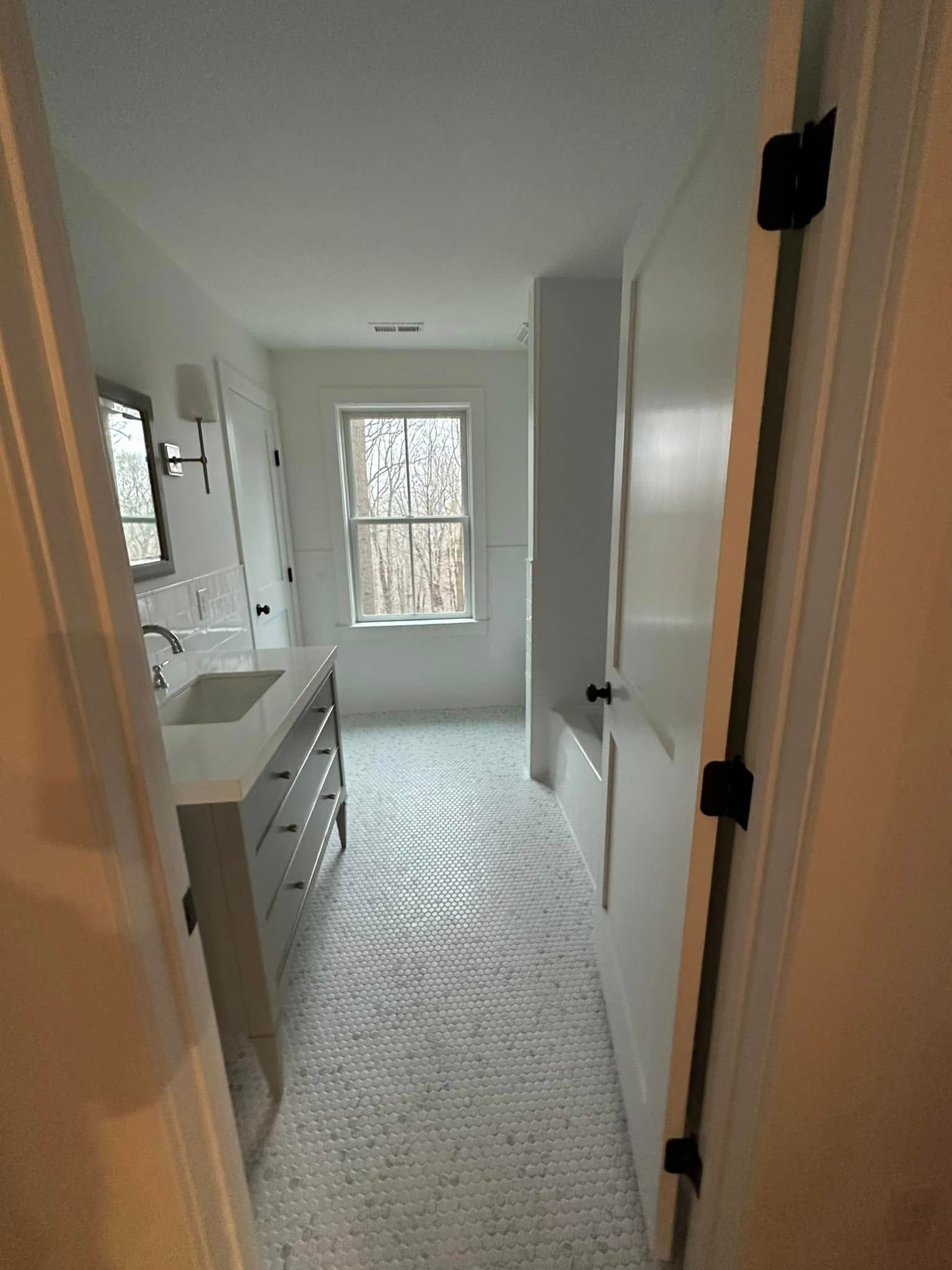 A bathroom with a sink , mirror , and window.