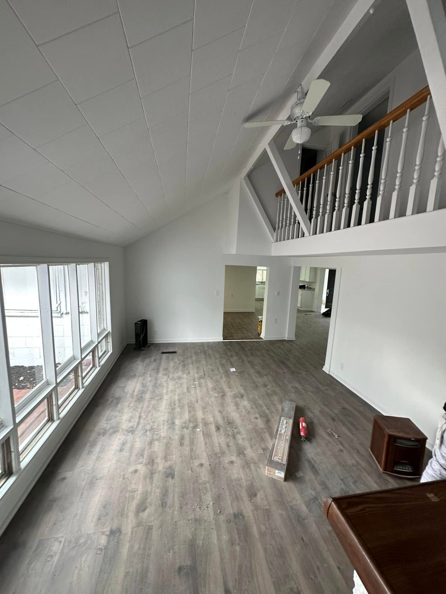 A large empty living room with hardwood floors and a ceiling fan.