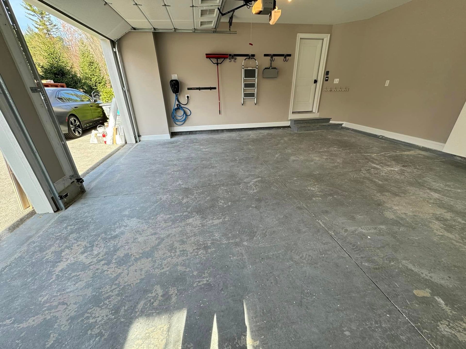 An empty garage with a green car parked in the background.