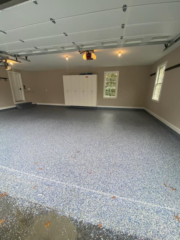 An empty garage with a blue floor and a garage door.