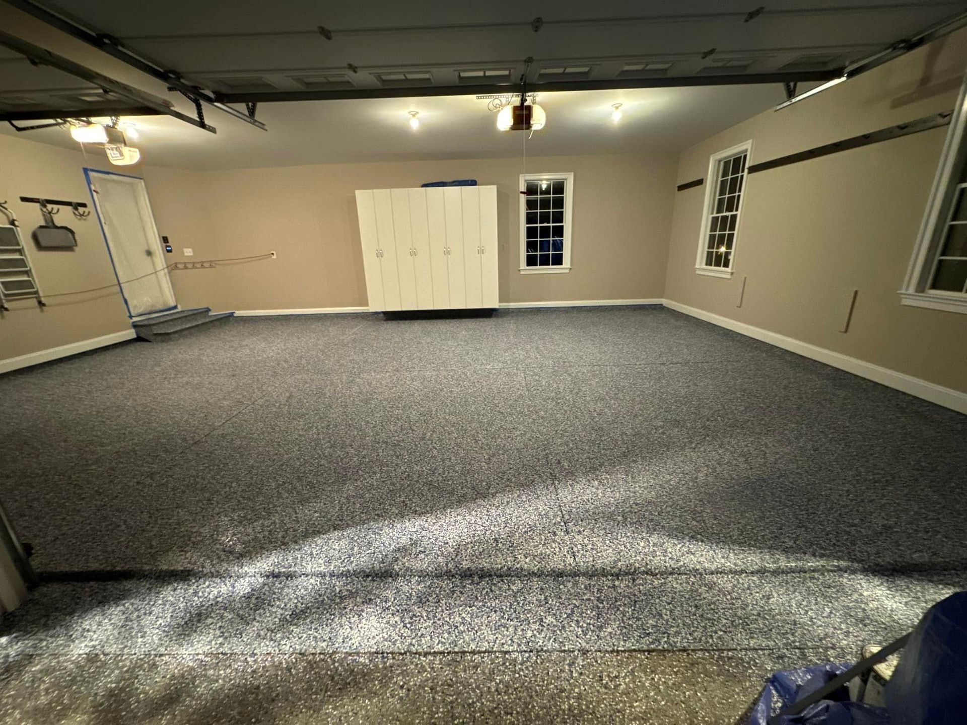 A garage with a carpeted floor and a garage door open.