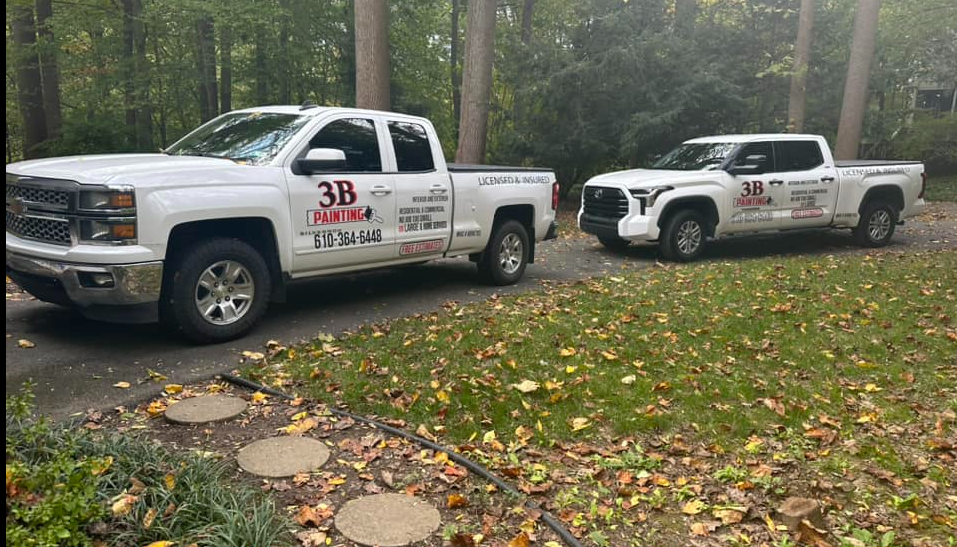 Two white trucks are parked next to each other in a driveway.