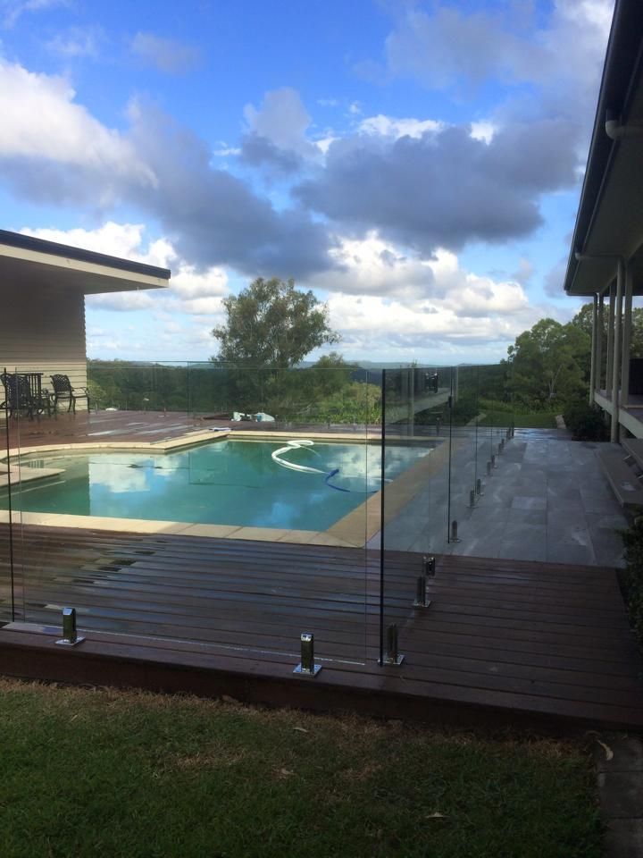 A Swimming Pool With a Glass Fence Around it — Frameless Shower Installations In Maroochydore, QLD