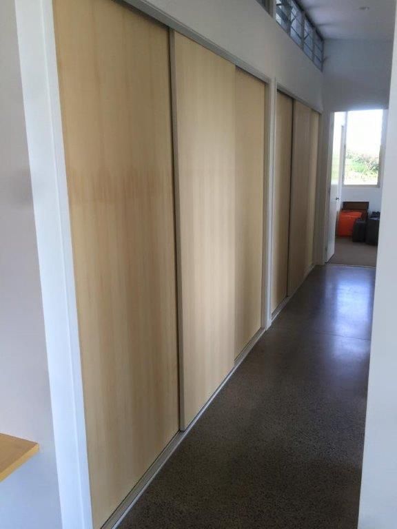 A Long Hallway With Sliding Wooden Doors In A House — Frameless Shower Installations In Maroochydore, QLD