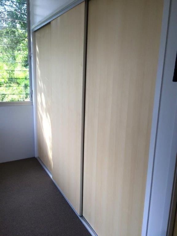 A Room With Sliding Wooden Doors and a Window — Frameless Shower Installations In Maroochydore, QLD 