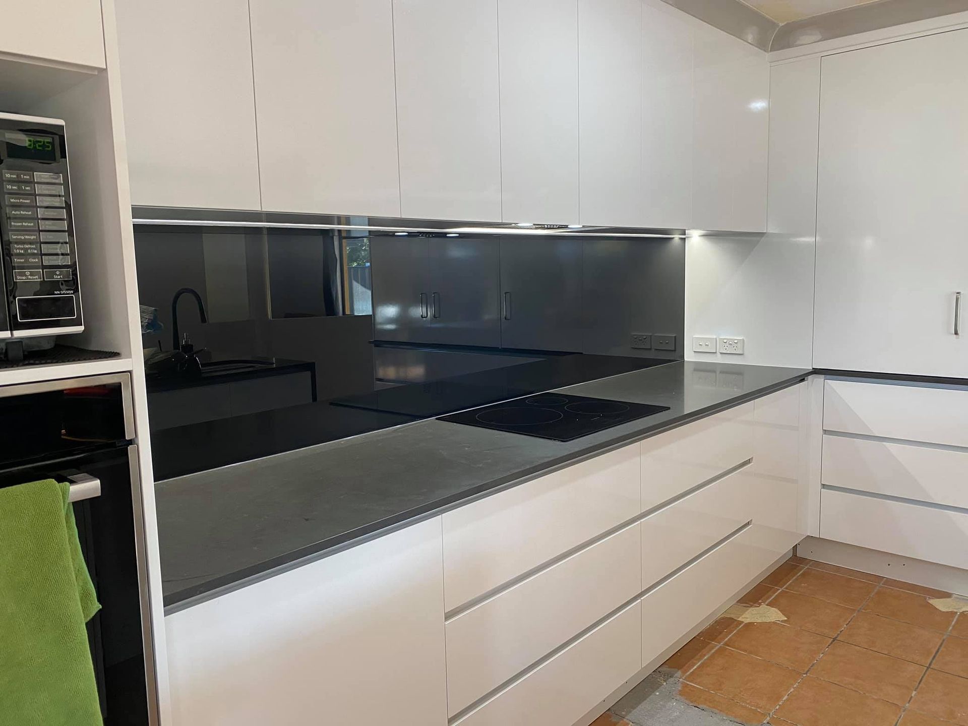 A Kitchen With White Cabinets and Black Counter Tops — Frameless Shower Installations In Maroochydore, QLD 