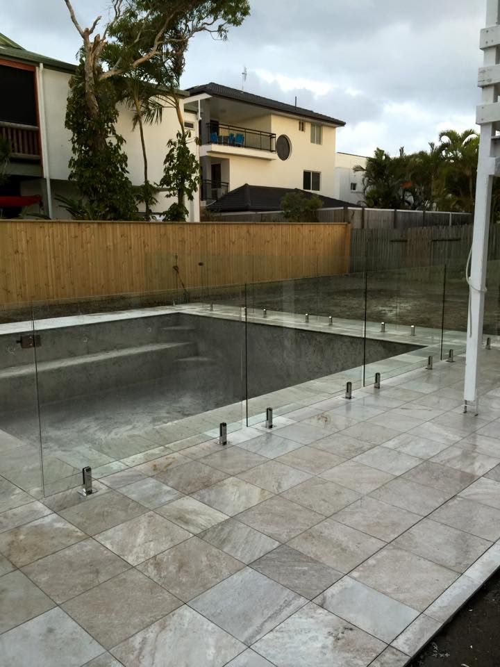 A Swimming Pool With a Glass Fence Around it — Frameless Shower Installations In Maroochydore, QLD