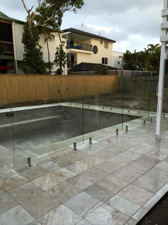 A Swimming Pool With A Glass Fence Around It — Frameless Shower Installations In Maroochydore, QLD
