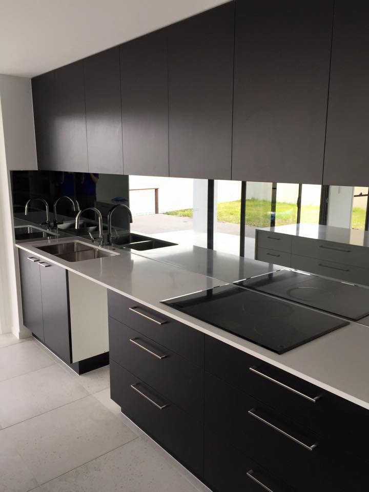 A Kitchen With Black Cabinets, a Sink, and a Stove Top Oven — Frameless Shower Installations In Mooloolaba, QLD