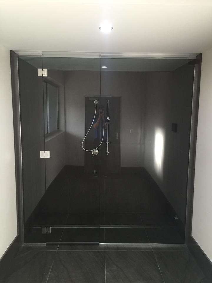A Dark Room With A Glass Door And A Window — Frameless Shower Installations In Maroochydore, QLD