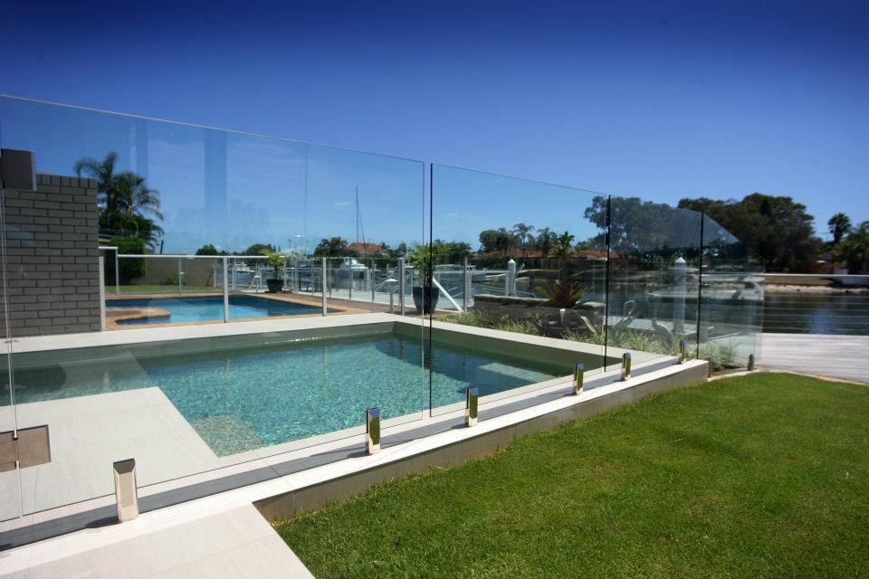 A Large Swimming Pool is Surrounded by a Glass Fence — Frameless Shower Installations In Mooloolaba, QLD 