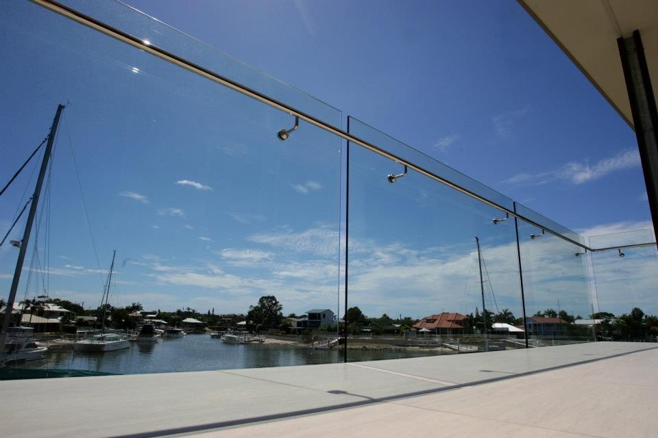 A Balcony With a Glass Railing Overlooking a Body of Water — Frameless Shower Installations In Mooloolaba, QLD 