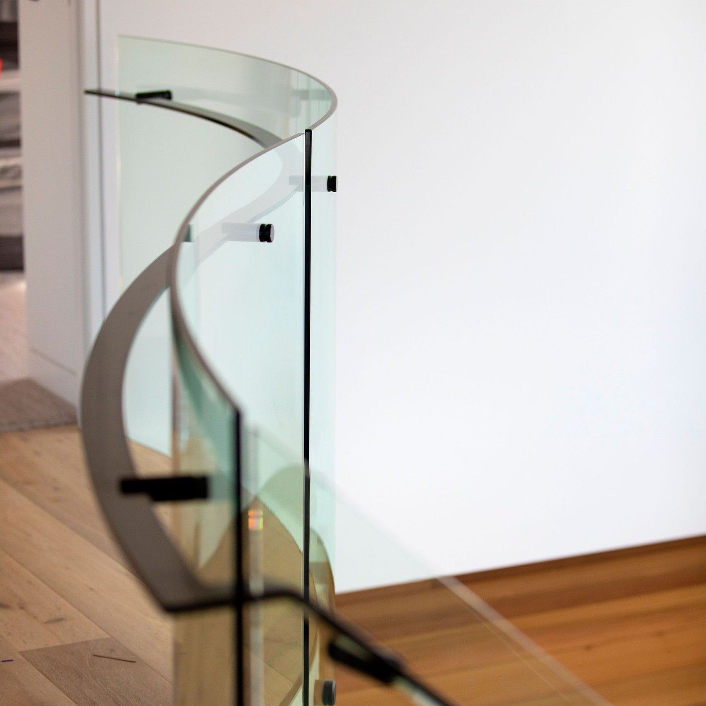 Curved Glass Railing With Black Supports on a Light Wood Floor — Frameless Shower Installations in Maroochydore, QLD