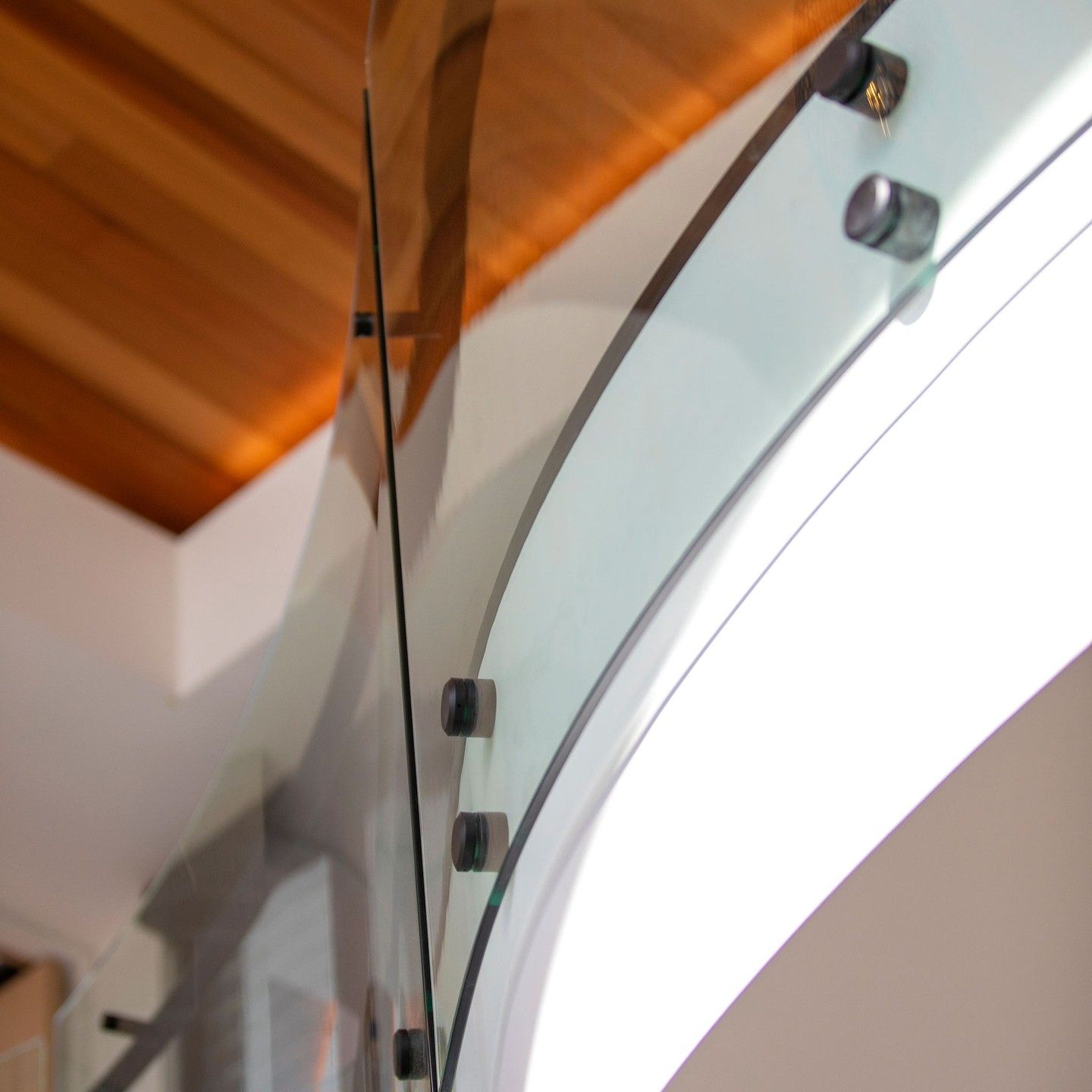 Curved Glass Panel Held by Black Hardware, With Wooden Ceiling Above — Frameless Shower Installations in Caloundra, QLD