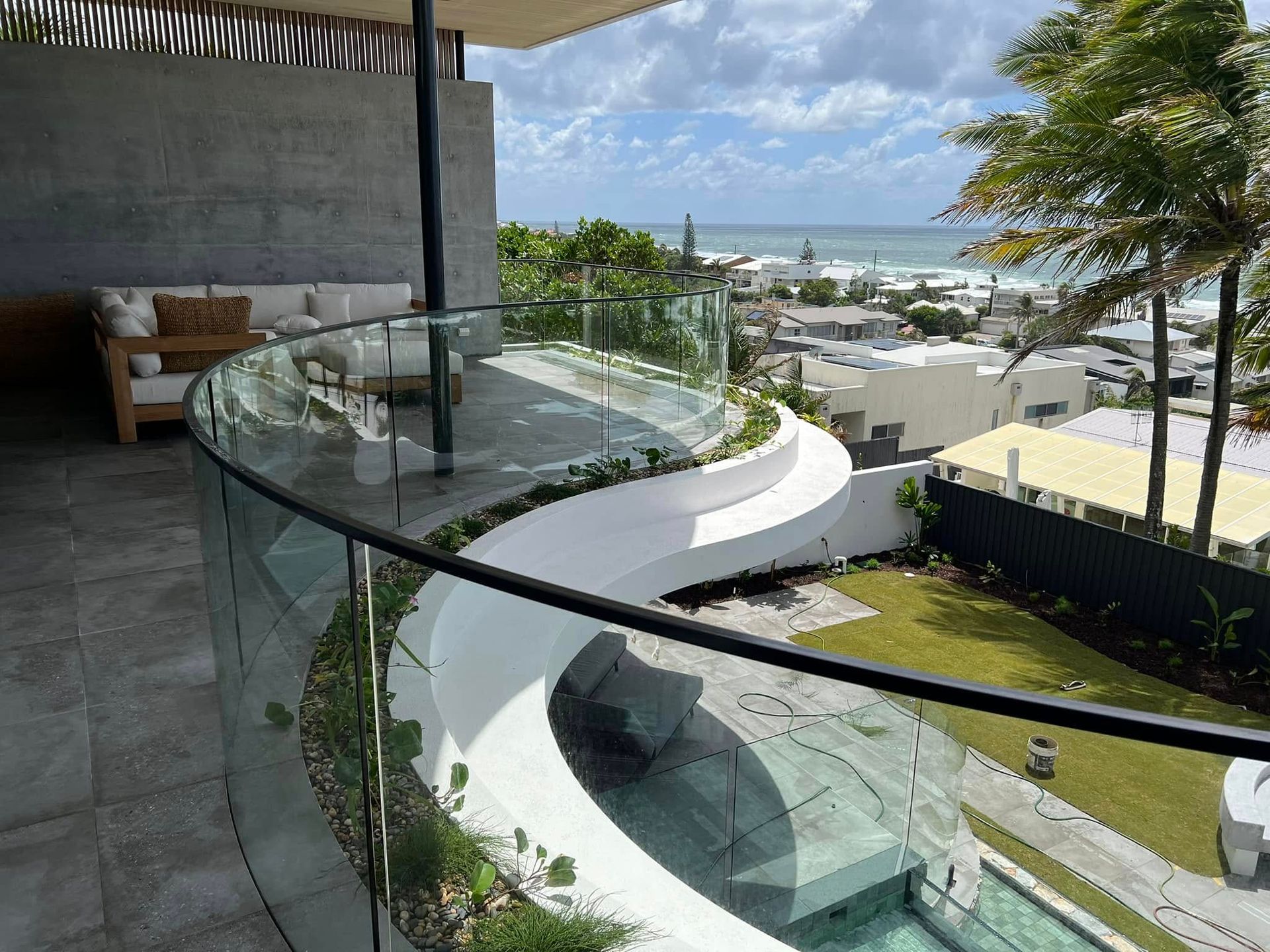 Balcony With Glass Railing Overlooking a Coastal Town— Frameless Shower Installations In Maroochydore, QLD