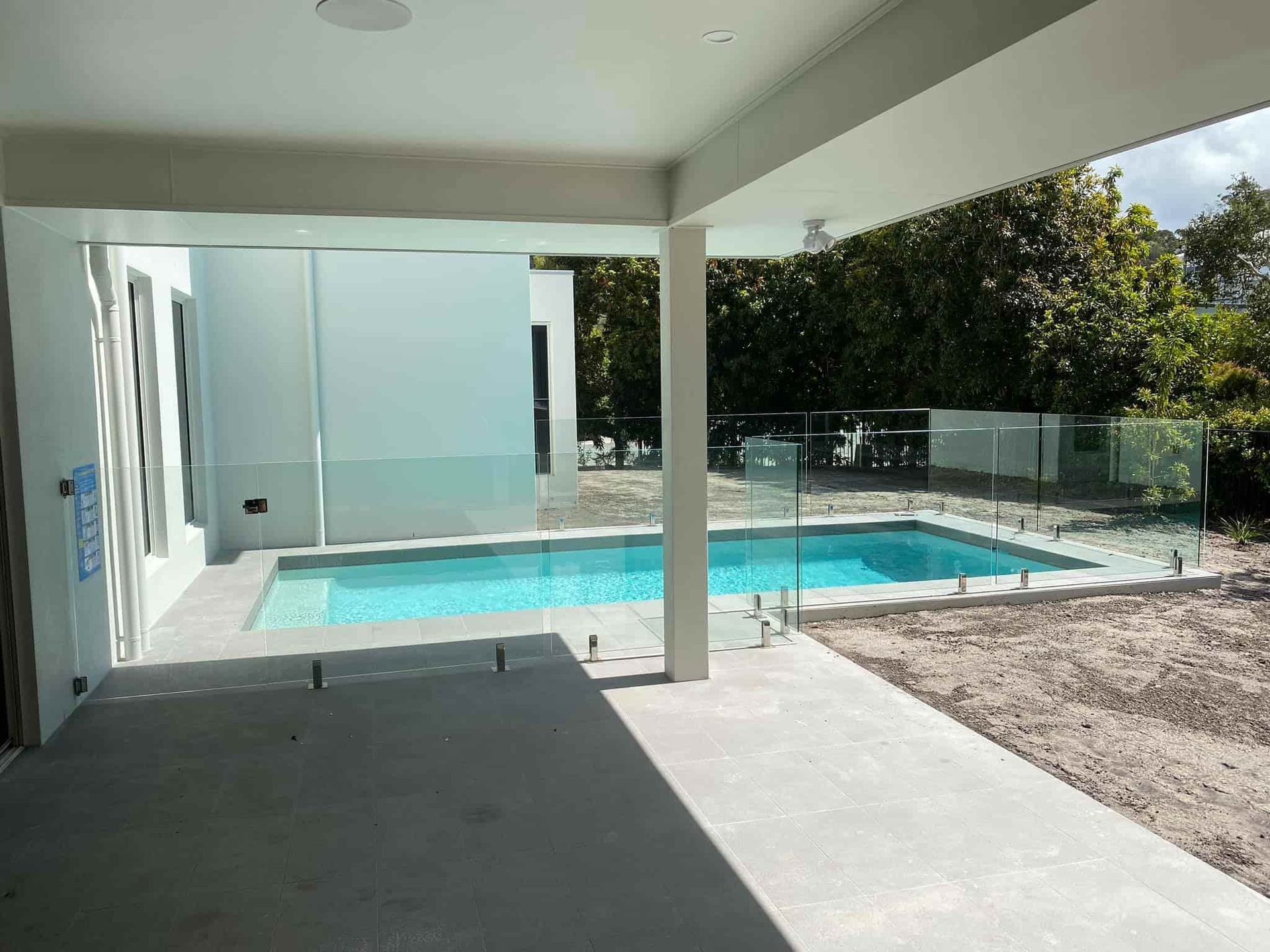 A Covered Patio Overlooks a Rectangular Pool Enclosed by Glass Fencing — Frameless Shower Installations In Maroochydore, QLD