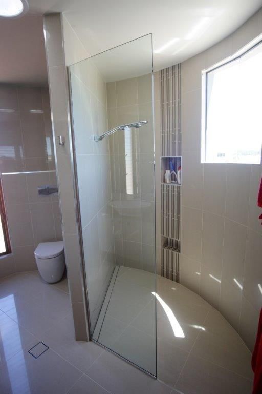 A Wooden Staircase With a Glass Railing and a Window — Frameless Shower Installations In Maroochydore, QLD 