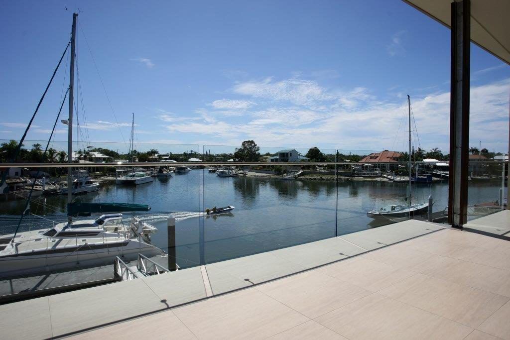 A Balcony Overlooking A Body Of Water With Boats Docked In It — Frameless Shower Installations In Maroochydore, QLD