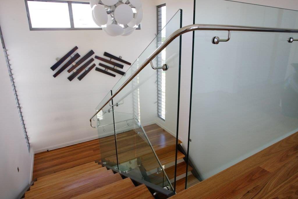 A Staircase With A Glass Railing And Wooden Steps — Frameless Shower Installations In Maroochydore, QLD