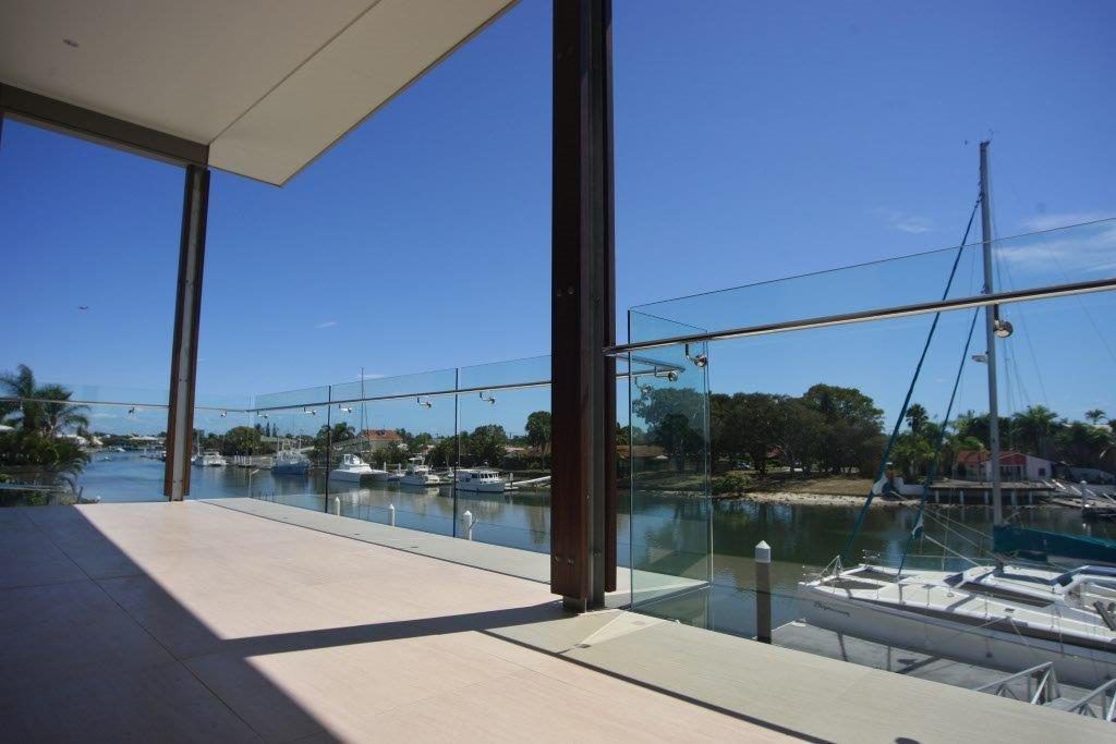 A Balcony With A Glass Railing Overlooking A Body Of Water — Frameless Shower Installations In Maroochydore, QLD