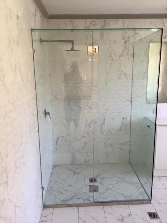 A Bathroom With A Glass Shower Door And Marble Tiles — Frameless Shower Installations In Maroochydore, QLD