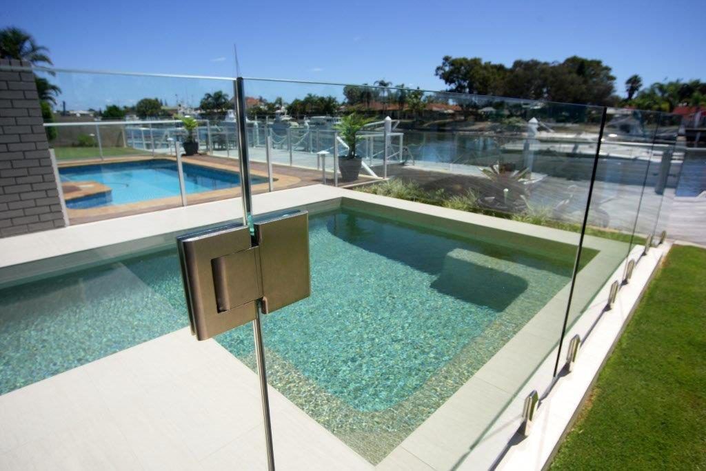 A Swimming Pool With A Glass Fence Around It — Frameless Shower Installations In Maroochydore, QLD