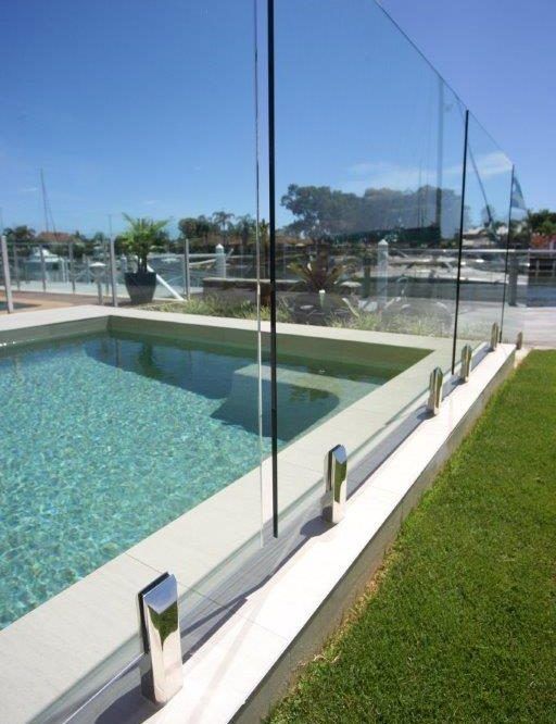 A Swimming Pool With a Glass Fence Around It — Frameless Shower Installations In Maroochydore, QLD 
