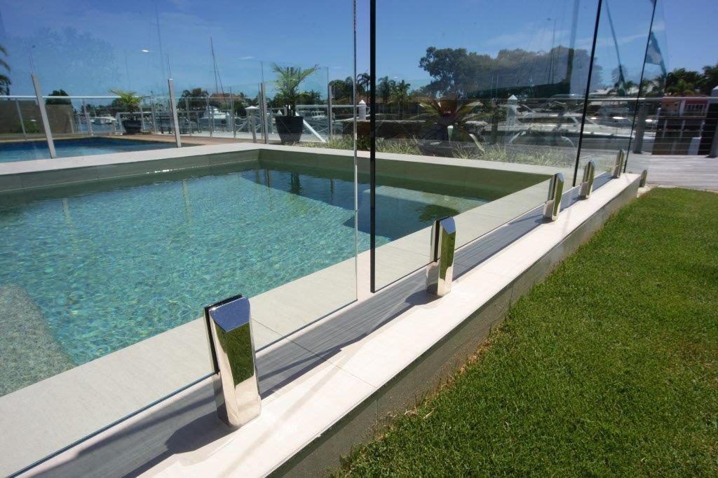 A Swimming Pool With a Glass Fence Around It — Frameless Shower Installations In Maroochydore, QLD 