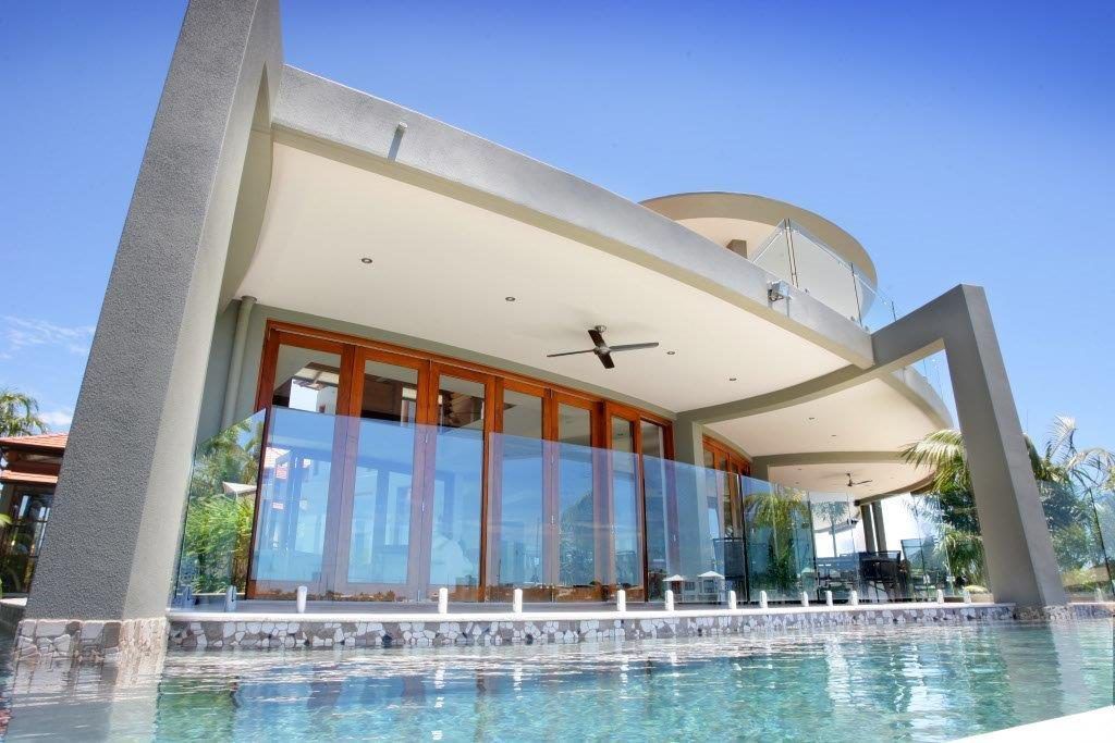 A Large House With A Swimming Pool In Front Of It — Frameless Shower Installations In Maroochydore, QLD