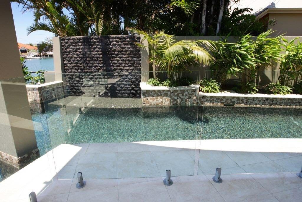 A Swimming Pool With A Glass Fence Around It — Frameless Shower Installations In Maroochydore, QLD