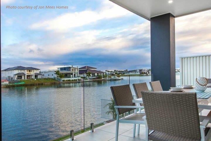 A Balcony With A Table And Chairs Overlooking A Body Of Water — Frameless Shower Installations In Maroochydore, QLD