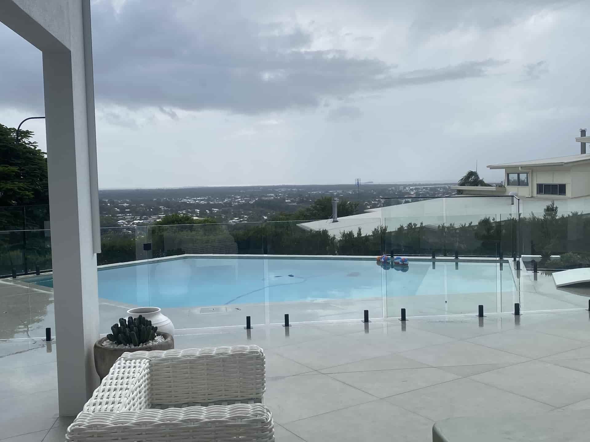 A Modern Pool with A City View on An Overcast Day — Frameless Shower Installations In Maroochydore, QLD