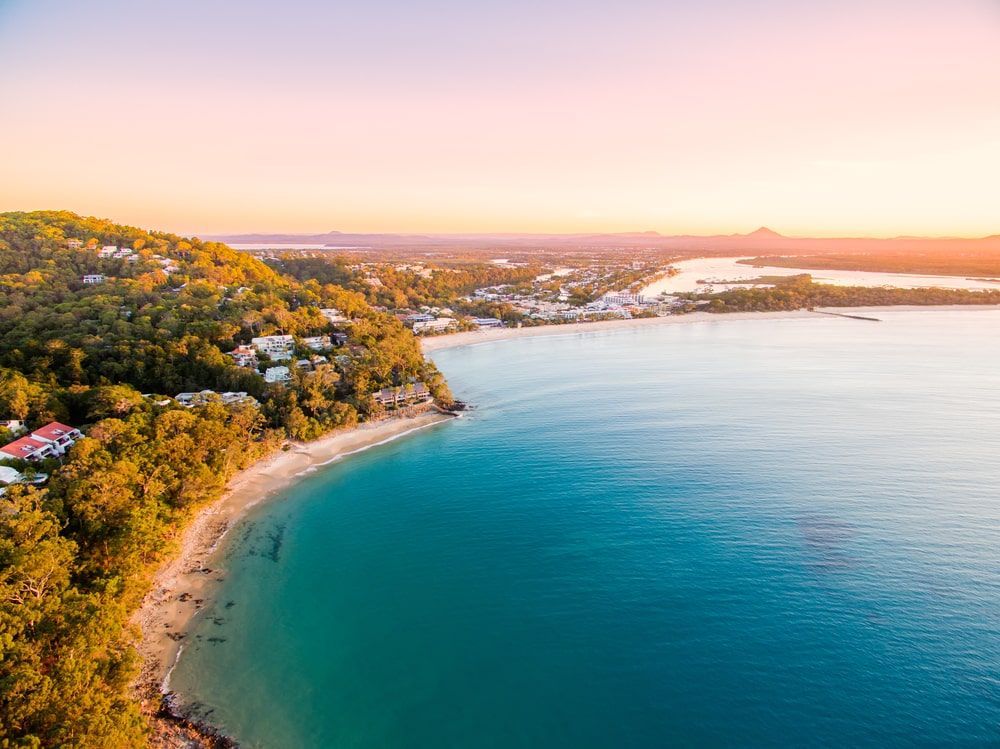 An Aerial View Of A Beach And A Body Of Water At Sunset — Frameless Shower Installations In Noosa, QLD