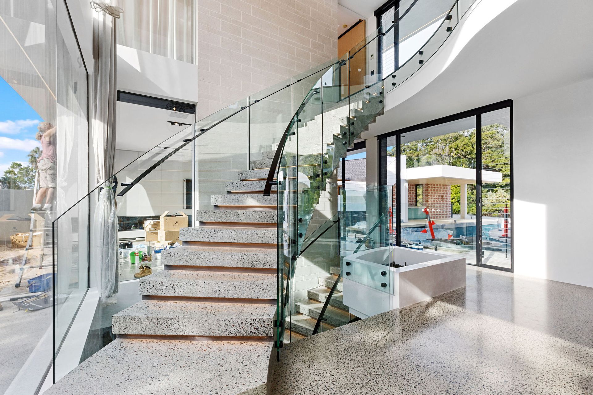 A Wooden Staircase With a Glass Railing and a Window — Frameless Shower Installations In Maroochydore, QLD 