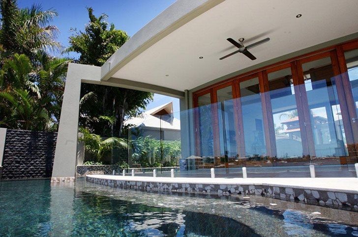 A Large House With A Swimming Pool In Front Of It — Frameless Shower Installations In Maroochydore, QLD